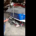 Image of a bass boat with a cover on it, and a man standing next to it.