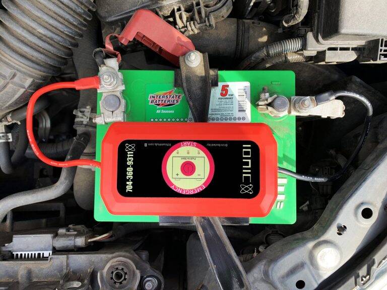 Lithium Ion emergency jump starter on top of car battery.
