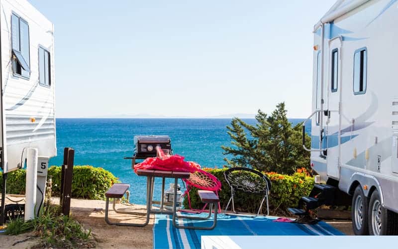 RV's parked by the ocean with picnic table in between.