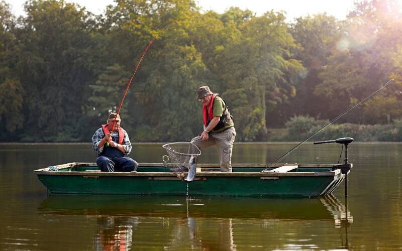 Two men fishing in a bass boat with a trolling motor.