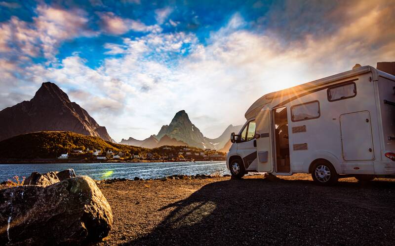 RV parked in front of a mountain stream.