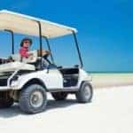 Man in golf cart on a beach.