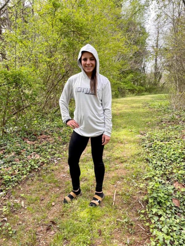 Girl wearing Ionic sportsmen hoodie on trail in woods.