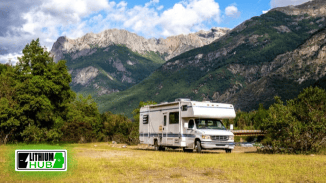RV parked in front of a beautiful mountain range and trees.