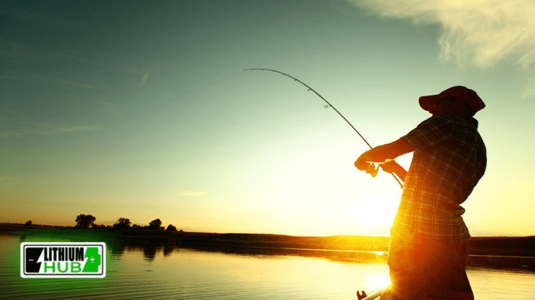 Image of a man fishing on a lake as the sun sets.