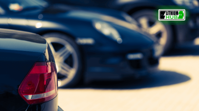Close-up image of a black car, featuring a green car in the background.