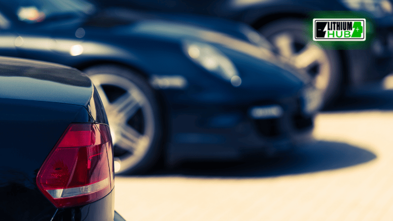 Close-up image of a black car, featuring a green car in the background.