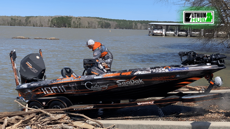 A man stands beside a lithiumhub battery on the side of a boat, looking out over the water.
