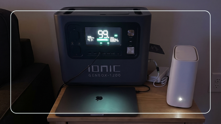 Ionic GenBox-1200 portable power station at 99% charge keeping a MacBook laptop and WiFi router running during a home blackout