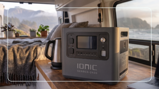 Ionic GenBox-2400 portable power station inside a camper van powering a kettle and laptop with a coastal ocean view through the window