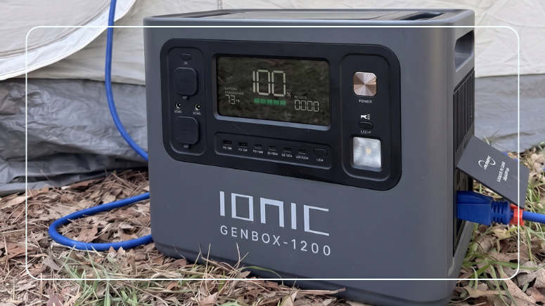 Ionic GenBox-1200 portable power station showing 100% charge next to a tent at a campsite