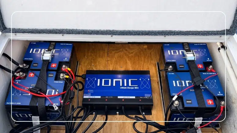 Four Ionic lithium deep cycle batteries installed in a fishing boat compartment with an Ionic Lithium Charger MC4 mounted in the center and clean strapped wiring