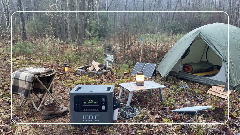 Ionic lithium portable power station at a quiet tent campsite with a solar panel and camp lantern