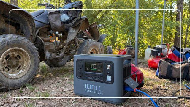 Ionic GenBox 1200 portable power station running at an outdoor trail site beside an ATV and gas fuel cans