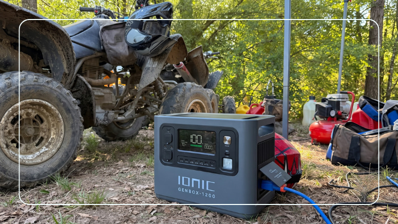 Ionic GenBox 1200 portable power station running at an outdoor trail site beside an ATV and gas fuel cans