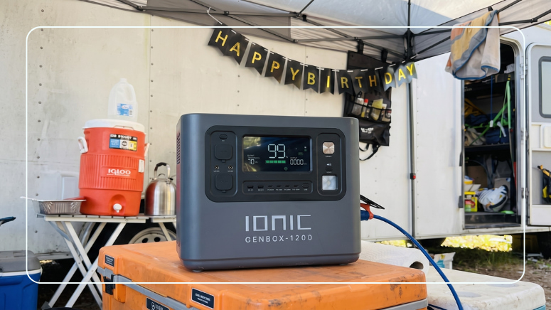 Ionic GenBox 1200 portable power station providing quiet backup power at a campsite gathering beside a trailer