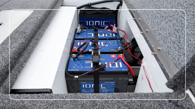 Ionic lithium deep cycle marine batteries wired and strapped inside a boat battery compartment with an Ionic on-board charger mounted above