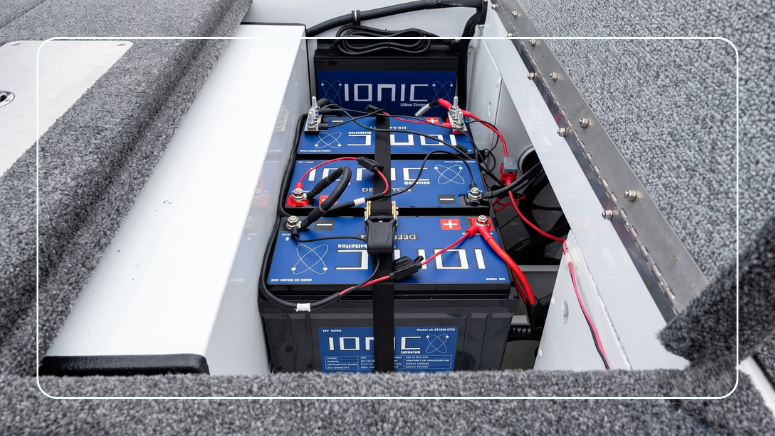 Ionic lithium deep cycle marine batteries wired and strapped inside a boat battery compartment with an Ionic on-board charger mounted above