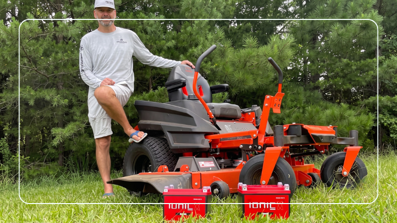 Two red Ionic lithium starter batteries staged on a zero-turn mower deck for a battery upgrade