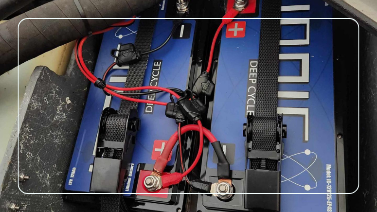 Two Ionic 12V lithium batteries strapped in a boat compartment with fused charger leads on each battery