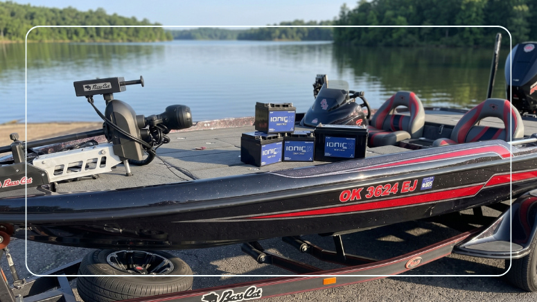 Ionic deep cycle lithium batteries on the deck of a bass boat at a lakeside boat ramp
