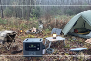Ionic lithium portable power station at a quiet tent campsite with a solar panel and camp lantern