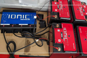 Ionic MC4 multi-bank lithium charger charging a row of Ionic batteries in a workshop