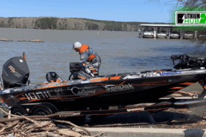 A man stands beside a lithiumhub battery on the side of a boat, looking out over the water.