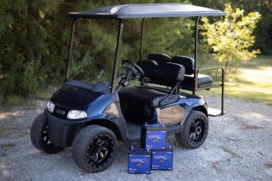 Golf cart on a golf course path with three Ionic lithium batteries with battery protection beside it on the path.
